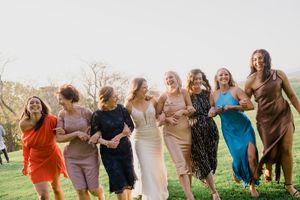 Group of friends joyfully running and jumping together in a grassy outdoor field on a cloudy day.