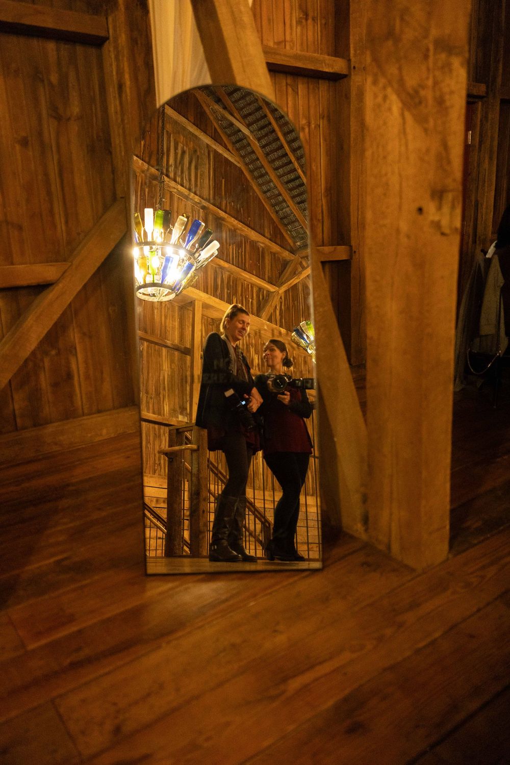 People stand in a dimly lit wooden corridor with angled walls and dramatic lighting creating atmospheric shadows.