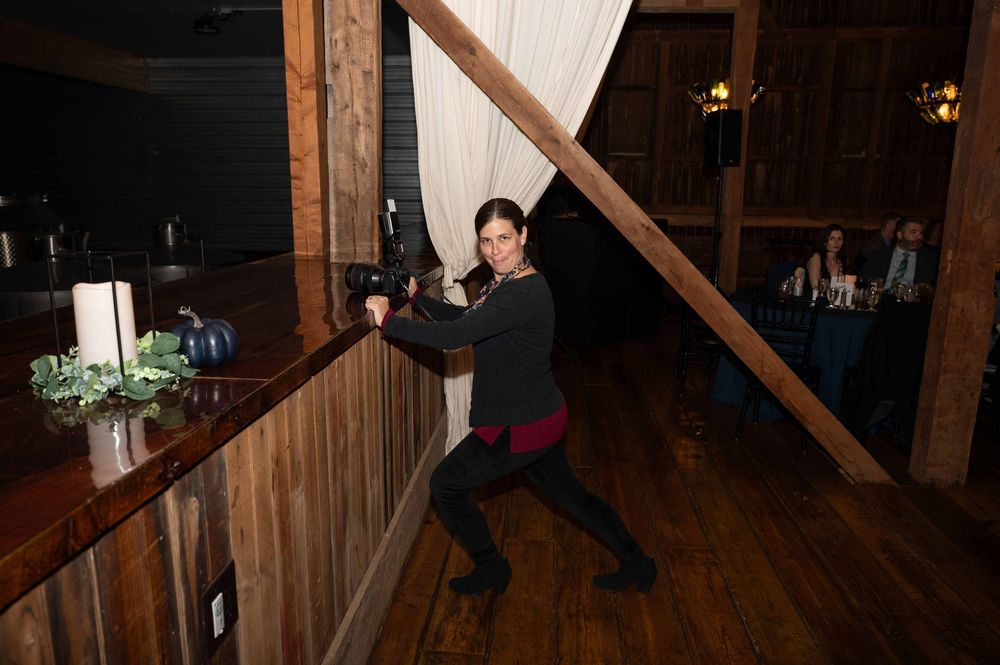 A rustic wooden dance floor with warm lighting in a barn-style venue creates an intimate wedding reception atmosphere.