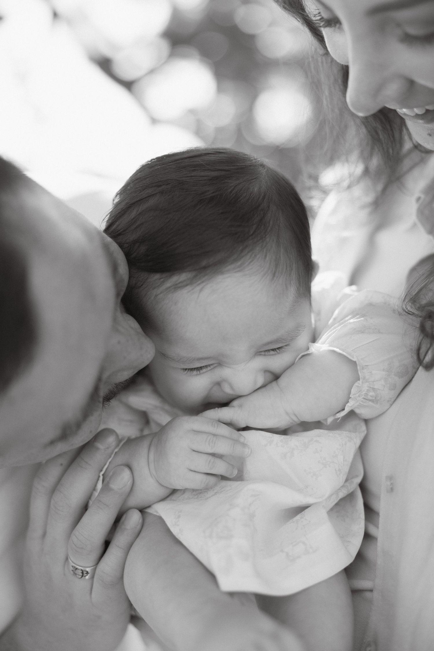Family session with parents kissing their baby girl during a candid moment