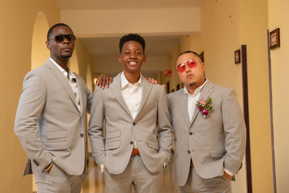 People in coordinated gray suits and white dress shirts stand together in an indoor hallway setting.