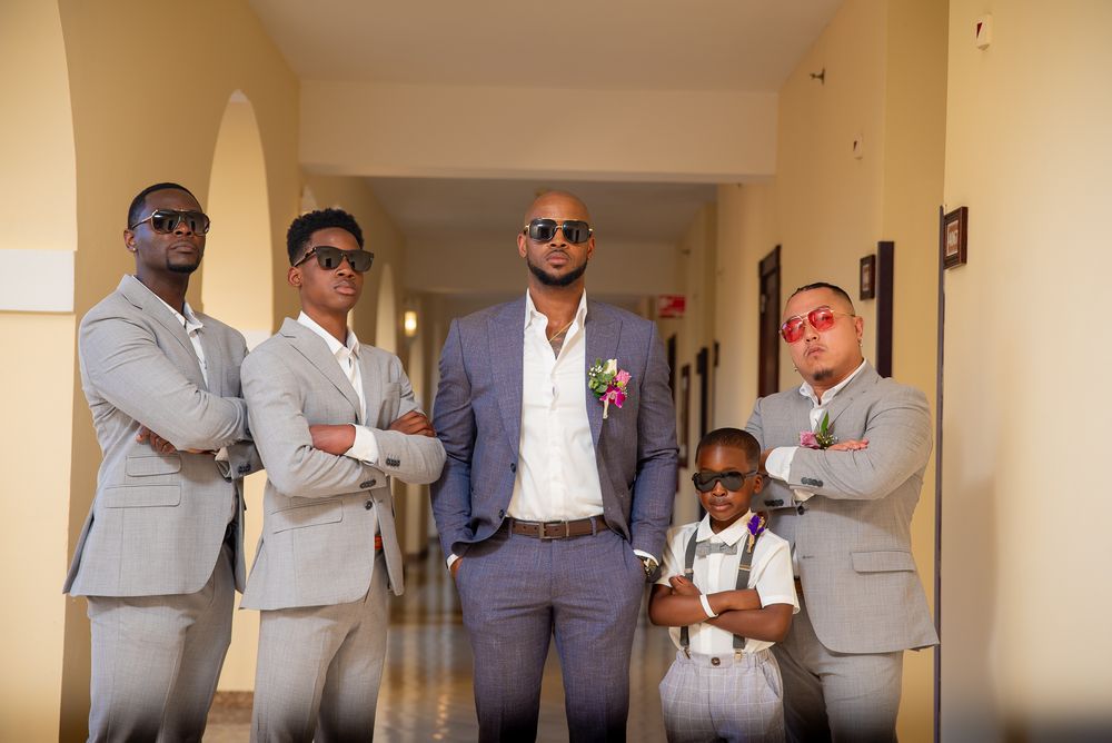 A group of people wearing matching light gray suits stand together in a hallway.