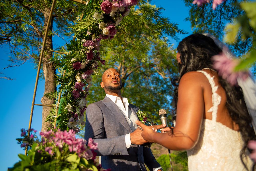 A couple shares a romantic moment outdoors with pink cherry blossoms blooming in the background.