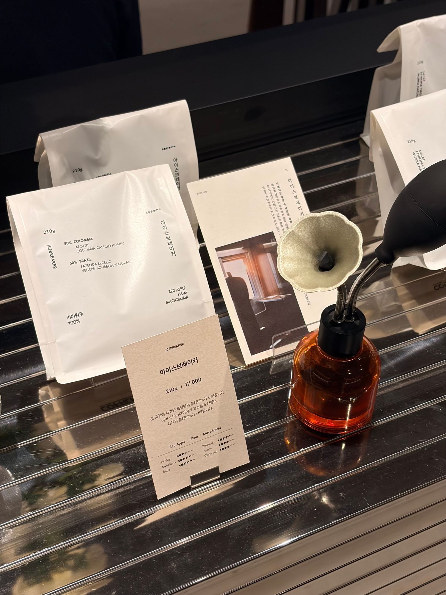 Amber glass bottle with dropper and ceramic funnel beside white product cards on a reflective surface.