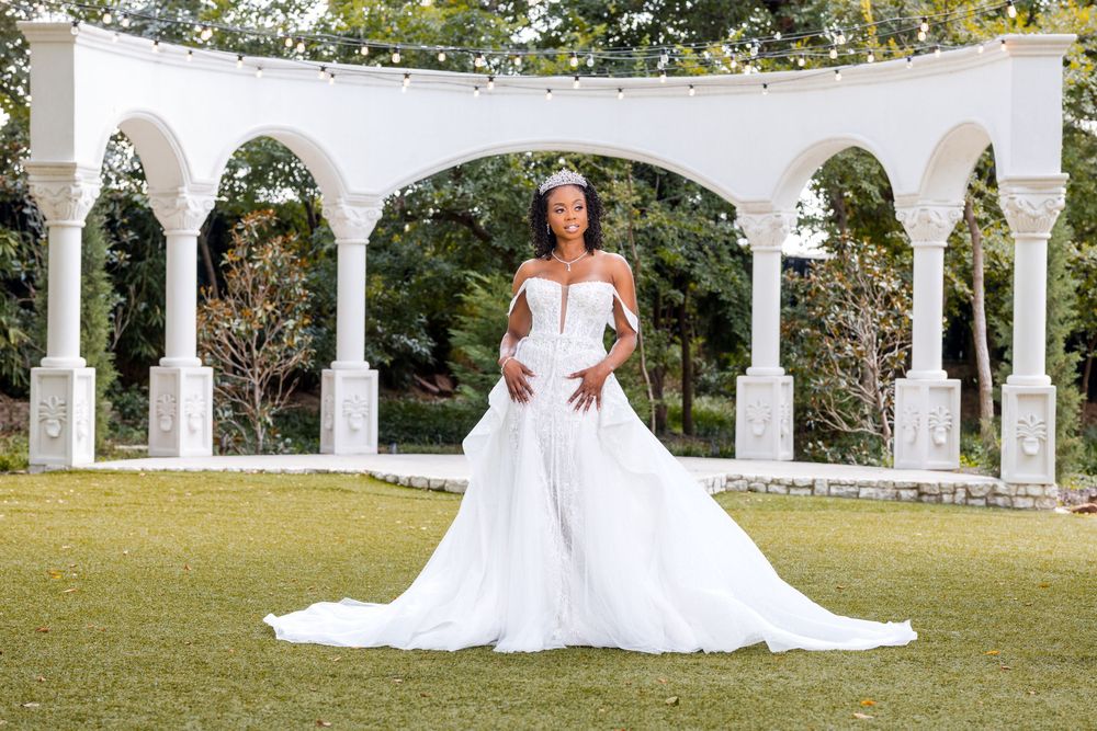 Elegant white wedding gown with sweetheart neckline and flowing train photographed under white garden arches outdoors.
