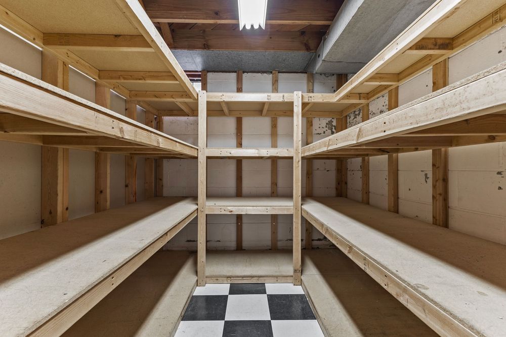 Empty wooden storage shelves lining walls of a clean room with checkered floor tiles.