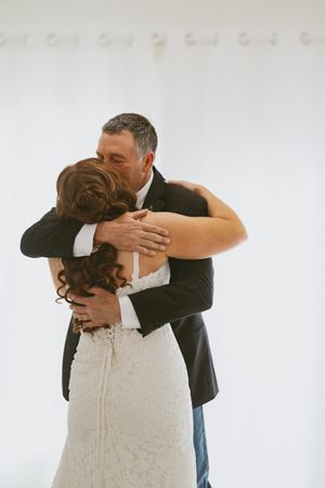 Bride and groom share an emotional embrace during their first dance at a wedding reception.
