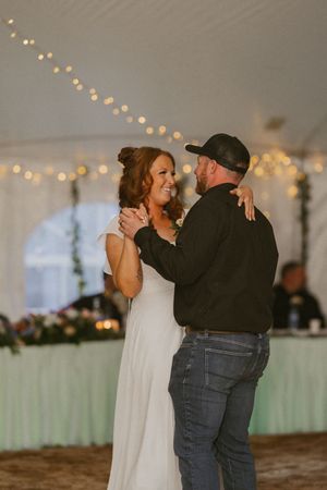 Bride and groom share their first dance under twinkling fairy lights at a romantic wedding reception.