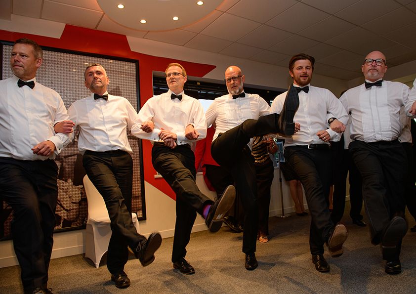 A line of performers in formal attire doing a synchronized dance routine.