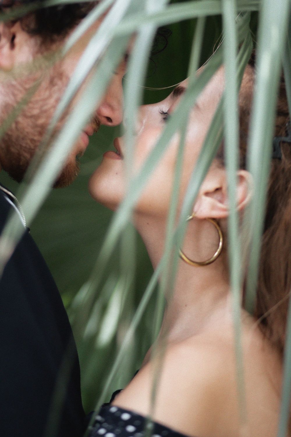 Couple kissing behind palm trees at Kendall Indian Hammocks Park Miami during engagement couples session.