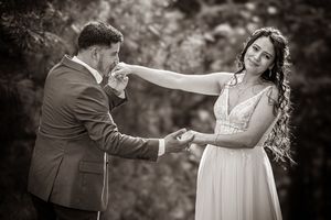 Groom kissing bride's hand in a romantic black and white outdoor wedding portrait.