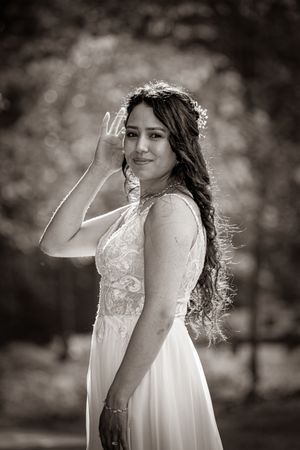 Black and white portrait of a bride in a white lace gown with floral crown, posing outdoors.