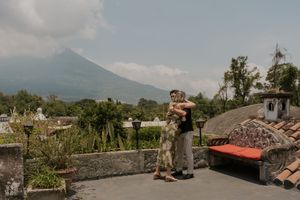 Couple embracing on a rooftop terrace with a stunning volcano and lush greenery backdrop.