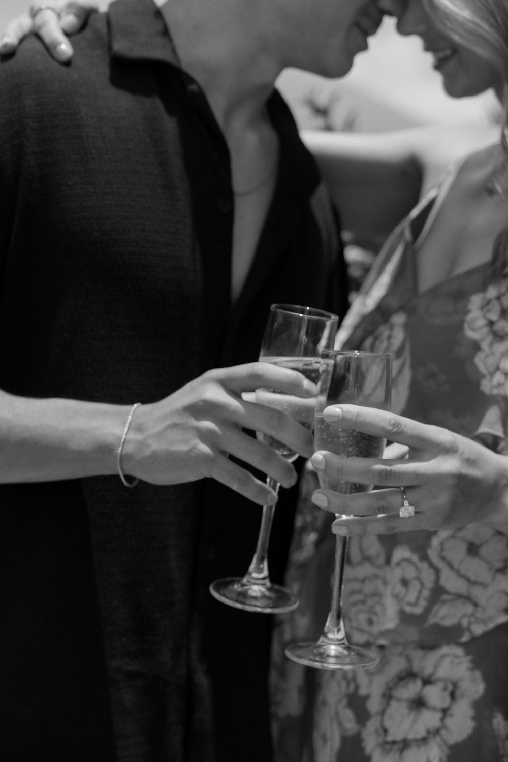 Couple clinking champagne glasses at a celebration, black and white photo.