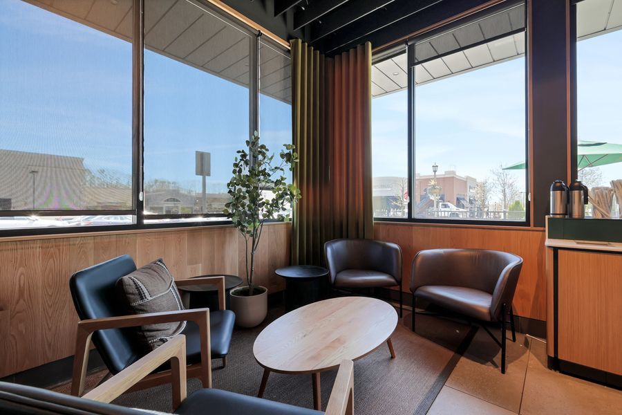 Modern lounge area with leather chairs, oval coffee table, and floor-to-ceiling windows overlooking city views.