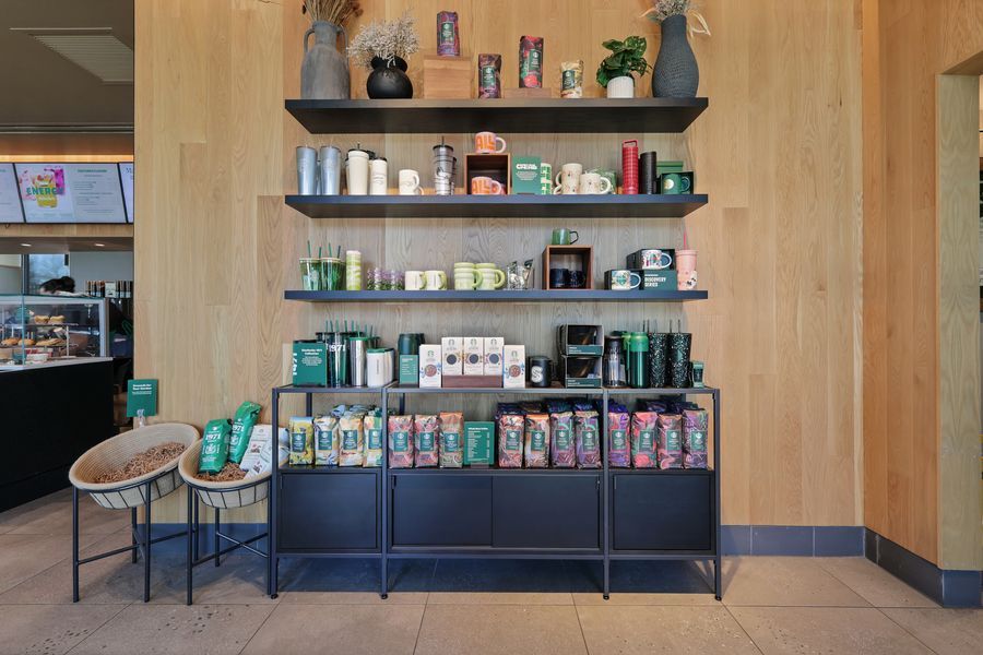 Retail display shelves with Starbucks merchandise, tumblers, mugs, and coffee bags in a modern store.