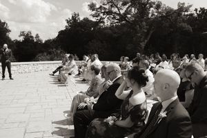 Black and white photo of wedding guests seated outdoors during a sunny ceremony.
