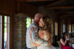 Bride and groom share intimate first dance embrace in rustic wood and stone venue.