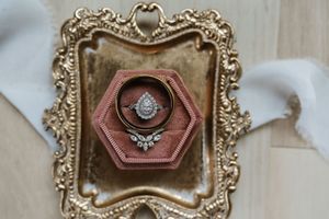 Elegant pear-shaped diamond engagement ring and wedding bands displayed in pink velvet hexagon ring box.