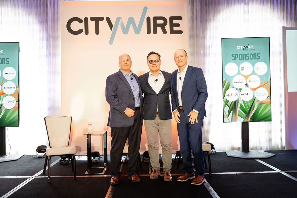 Three business professionals seated on stage during a panel discussion at a corporate conference event.