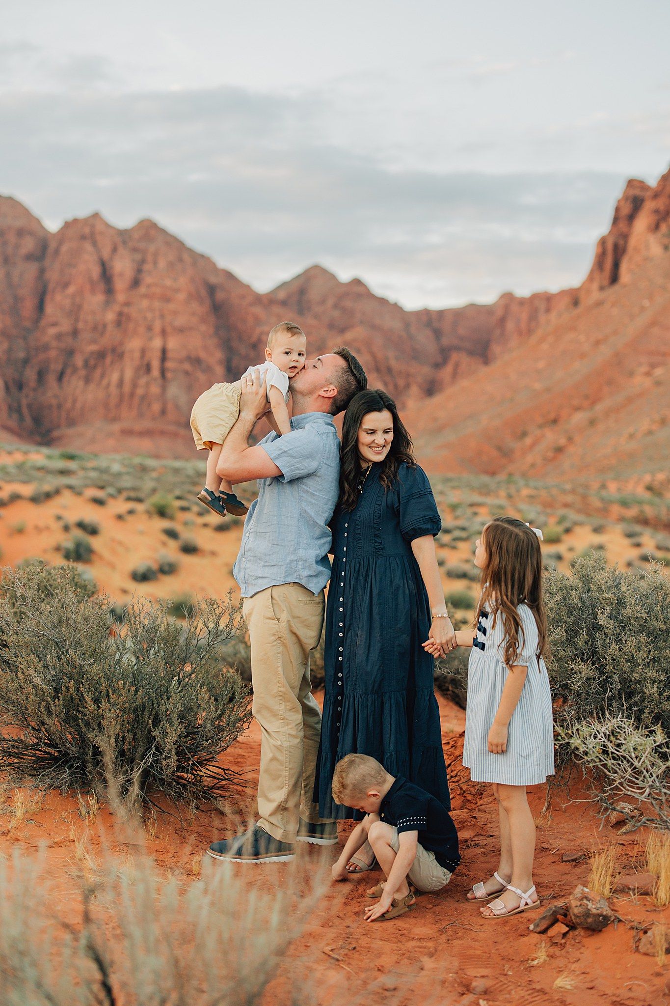 Family portrait in red rock desert landscape, parents with three children, rustic Southwest scenery backdrop.
