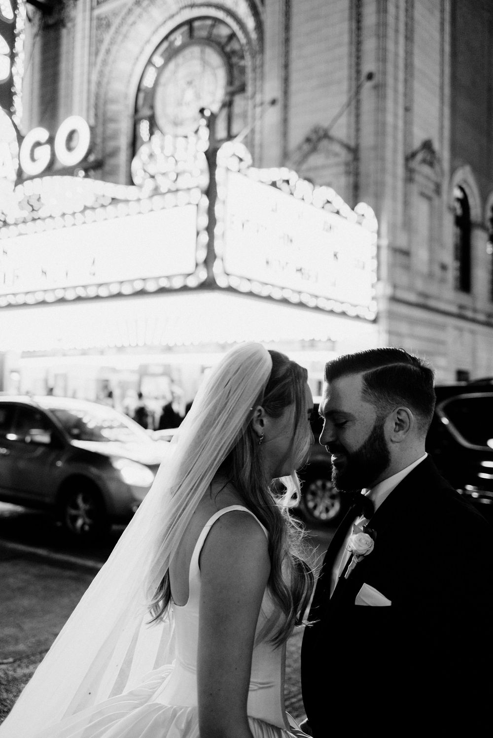 Black and white photo of a bride and groom sharing an intimate moment outside the Chicago Theatre.