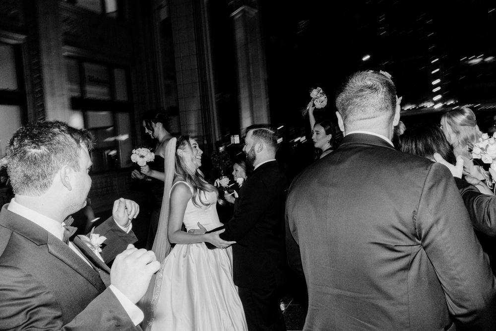 Black and white artistic photo of wedding party celebrating with the bride and groom at a reception.