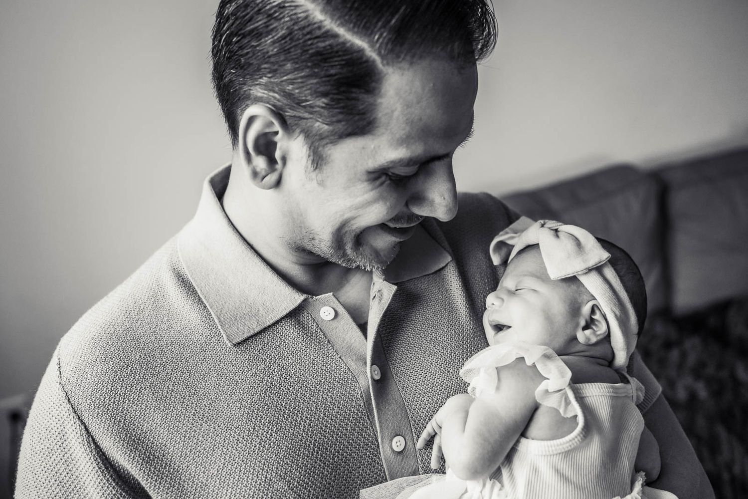 Black and white photo of dad with smiling newborn.
