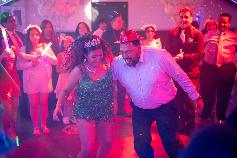 Couple dancing joyfully at a New Year's Eve party with colorful lights and festive crowd in background.