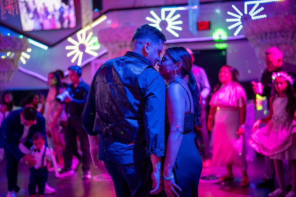 Couple sharing a romantic moment on a vibrant nightclub dance floor with colorful neon lights.
