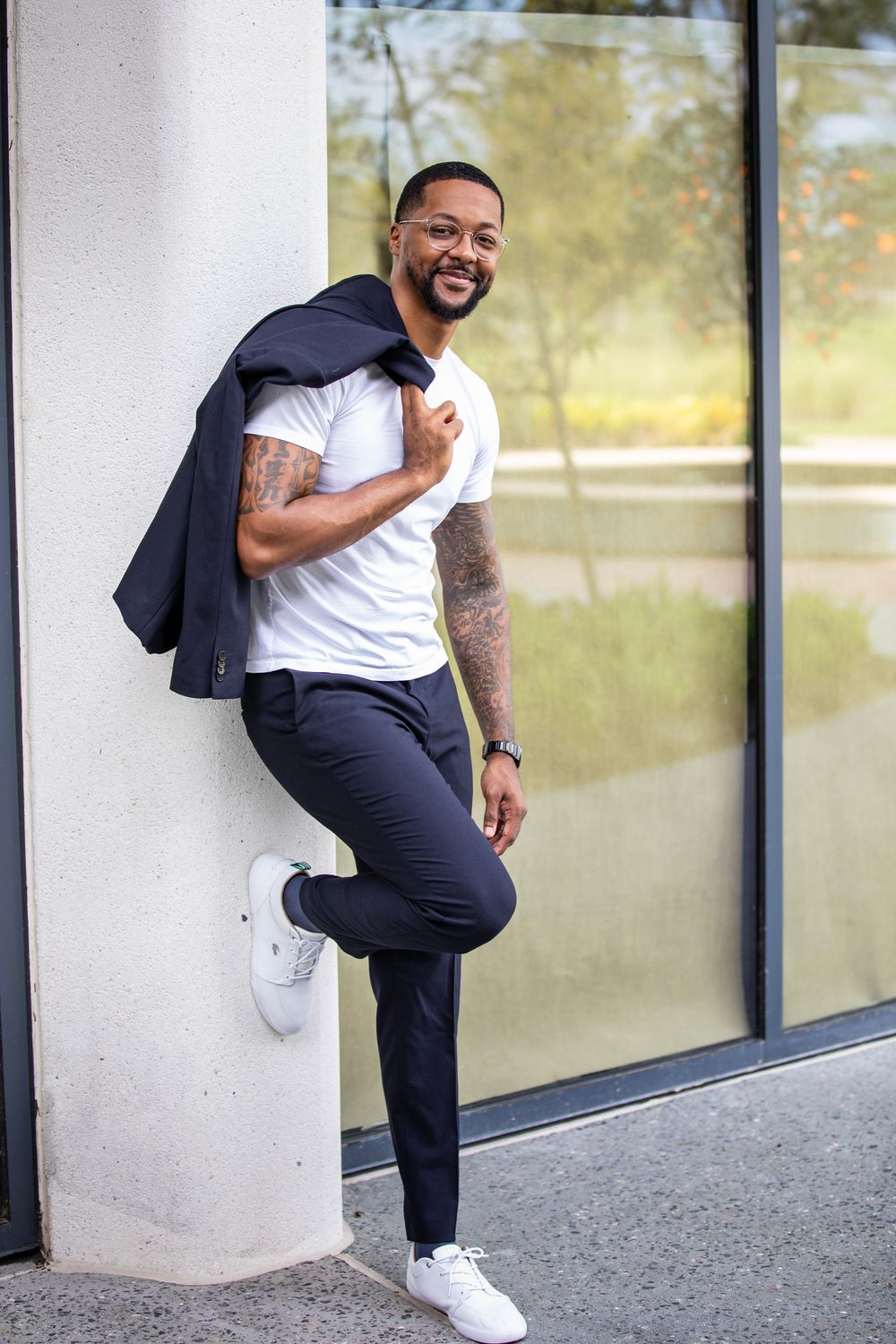 Stylish man in business casual attire poses against building exterior.