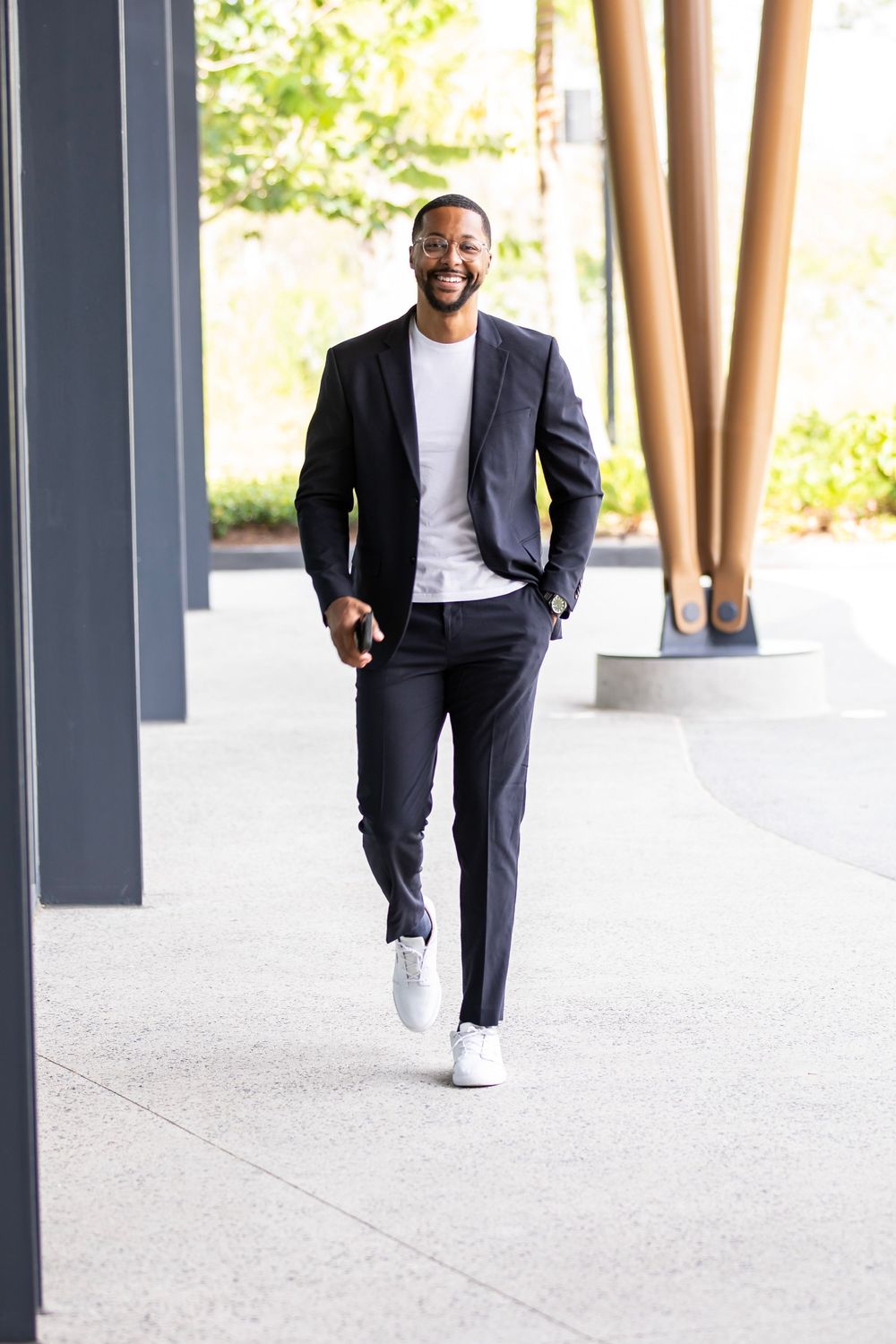 Professional in suit and sneakers walks confidently through modern building corridor.