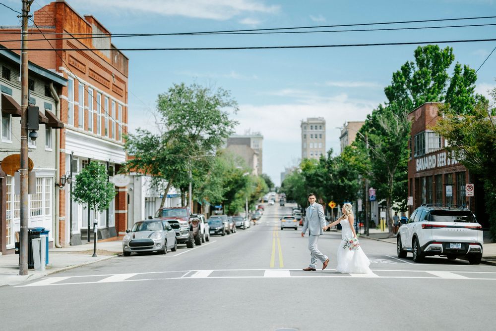 Bride and groom crossing a downtown street at a crosswalk on their wedding day.