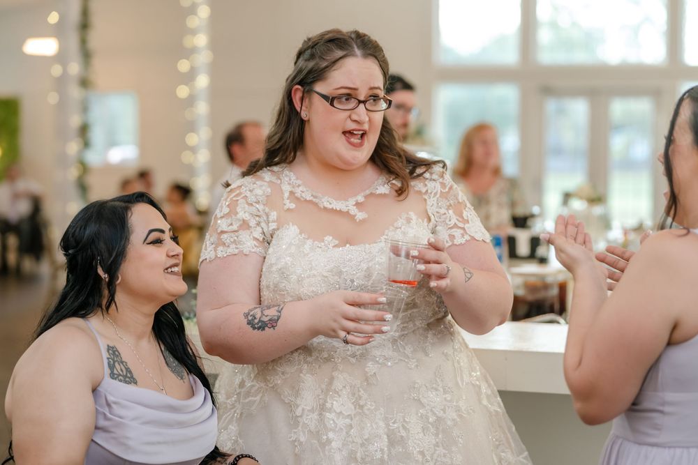 Bride in lace wedding gown laughing with guests at wedding reception celebration.
