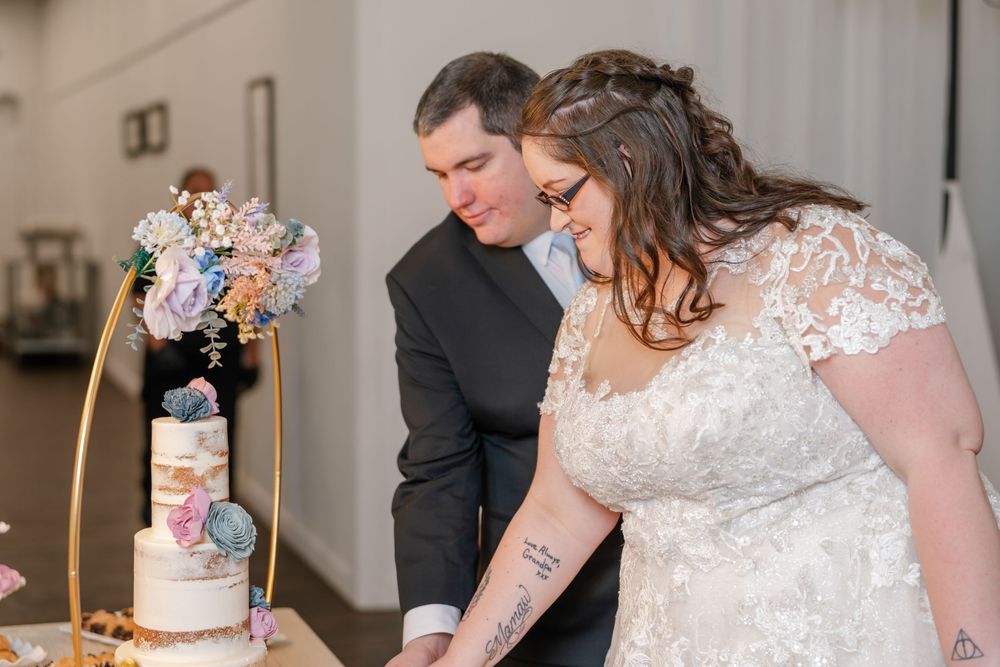 Bride and groom cutting their floral-topped wedding cake together during reception.