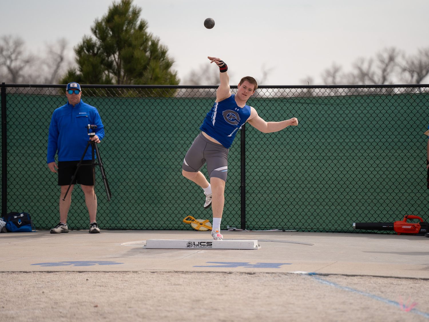 Track athlete performs shot put throw during outdoor competition.