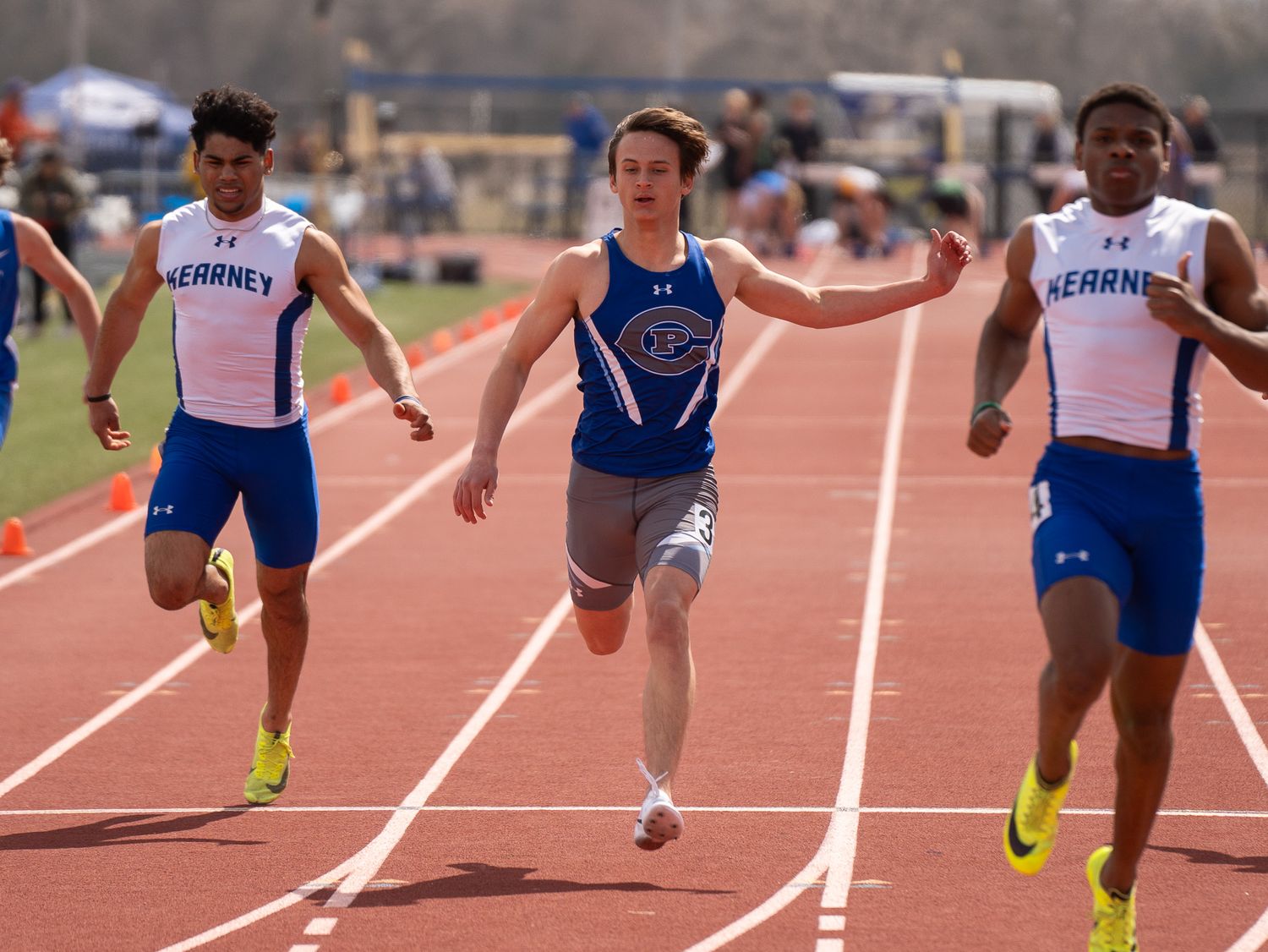 Sprinters compete neck and neck in an intense track race.