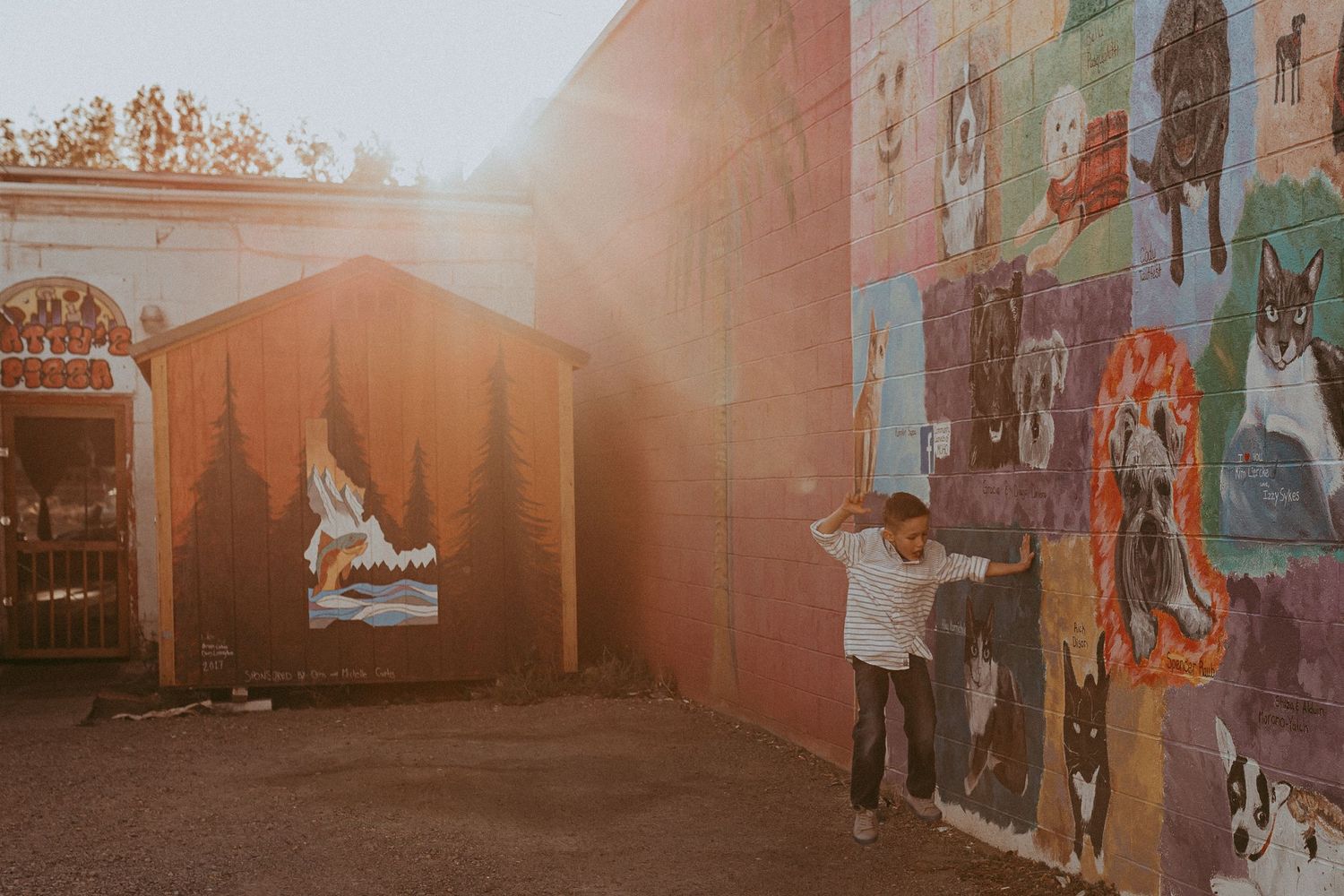 A boy jumps near a mural with light rays shining down. Whitney Popp photographer.