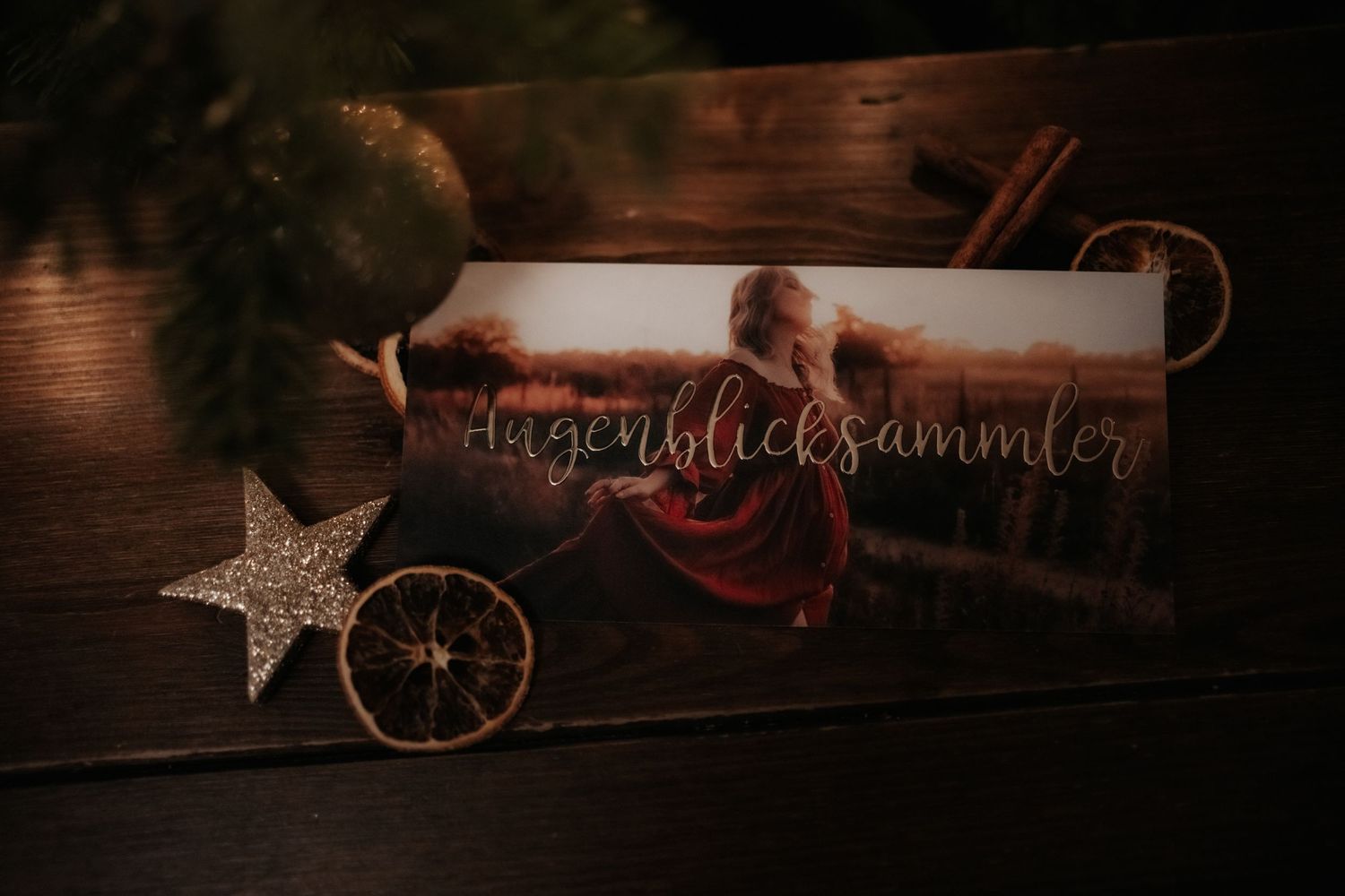 A rustic holiday decoration with a glowing star ornament and red ribbon against a dark wooden surface.