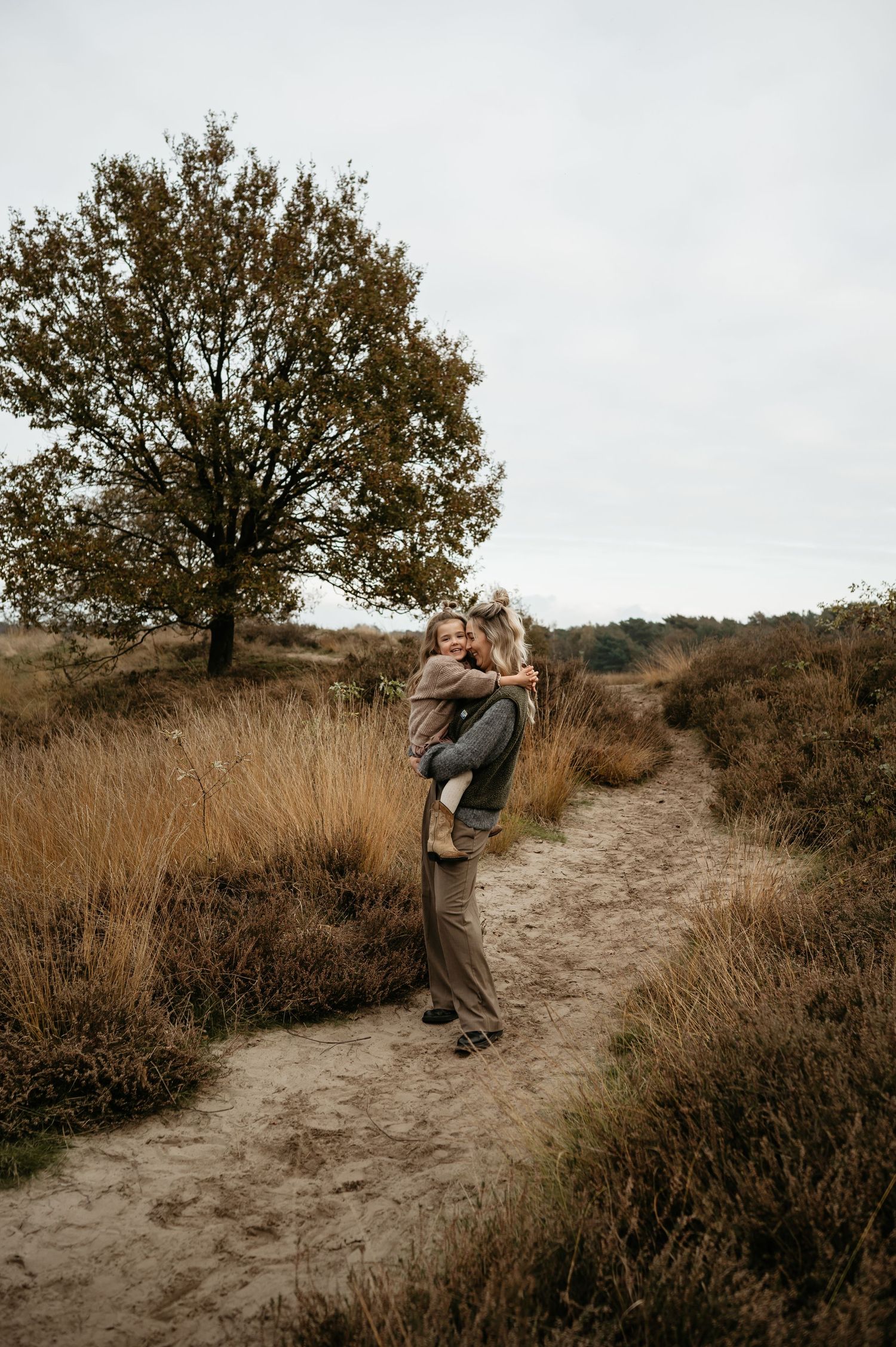 Een mama met haar zoontje knuffelen met elkaar tijdens een familiefotoshoot in de natuur. Kinderfotografie natuurlijke omgeving.