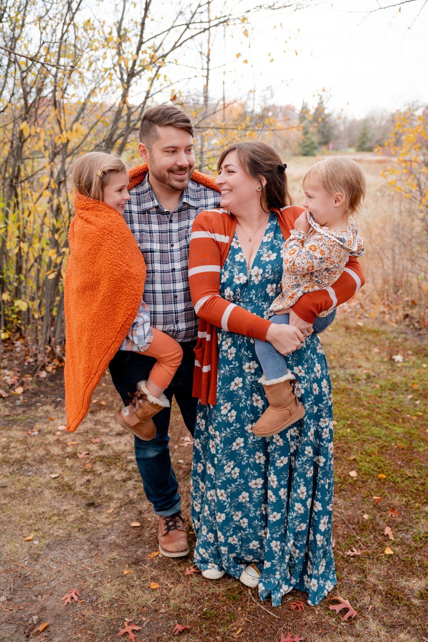 A family shares a joyful moment together in autumn wearing coordinating orange and blue outfits.