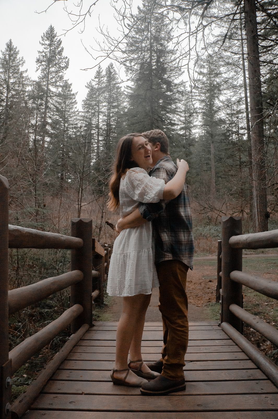 Couple wrapped in an embrace on a rustic wooden bridge during romantic photo session in Salem OR