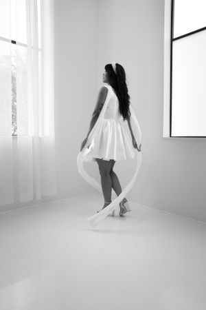 Black and white photo of a bride in a short dress twirling with her veil.