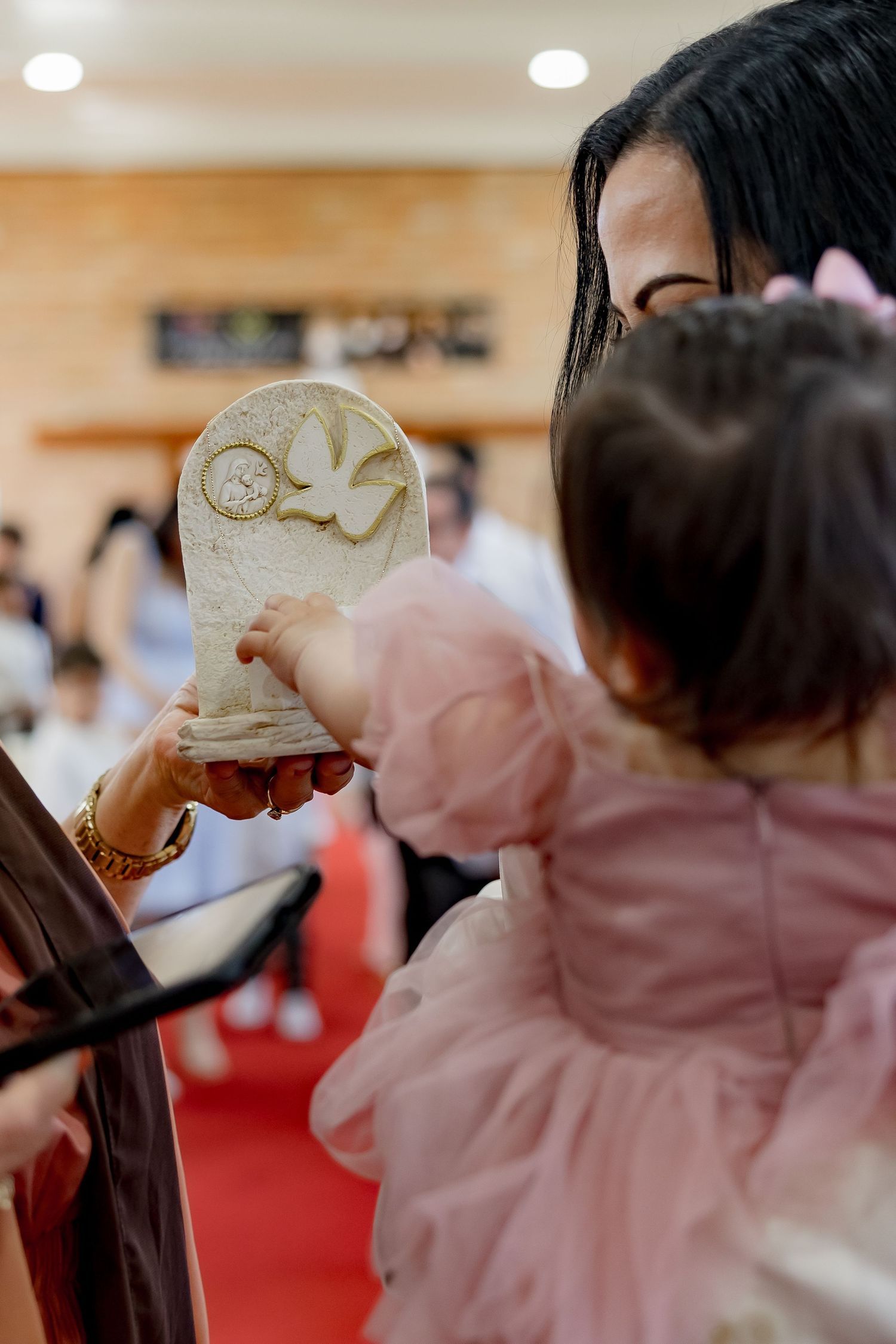 Baby holds a religious ceremonial item during a christening service at a church.
