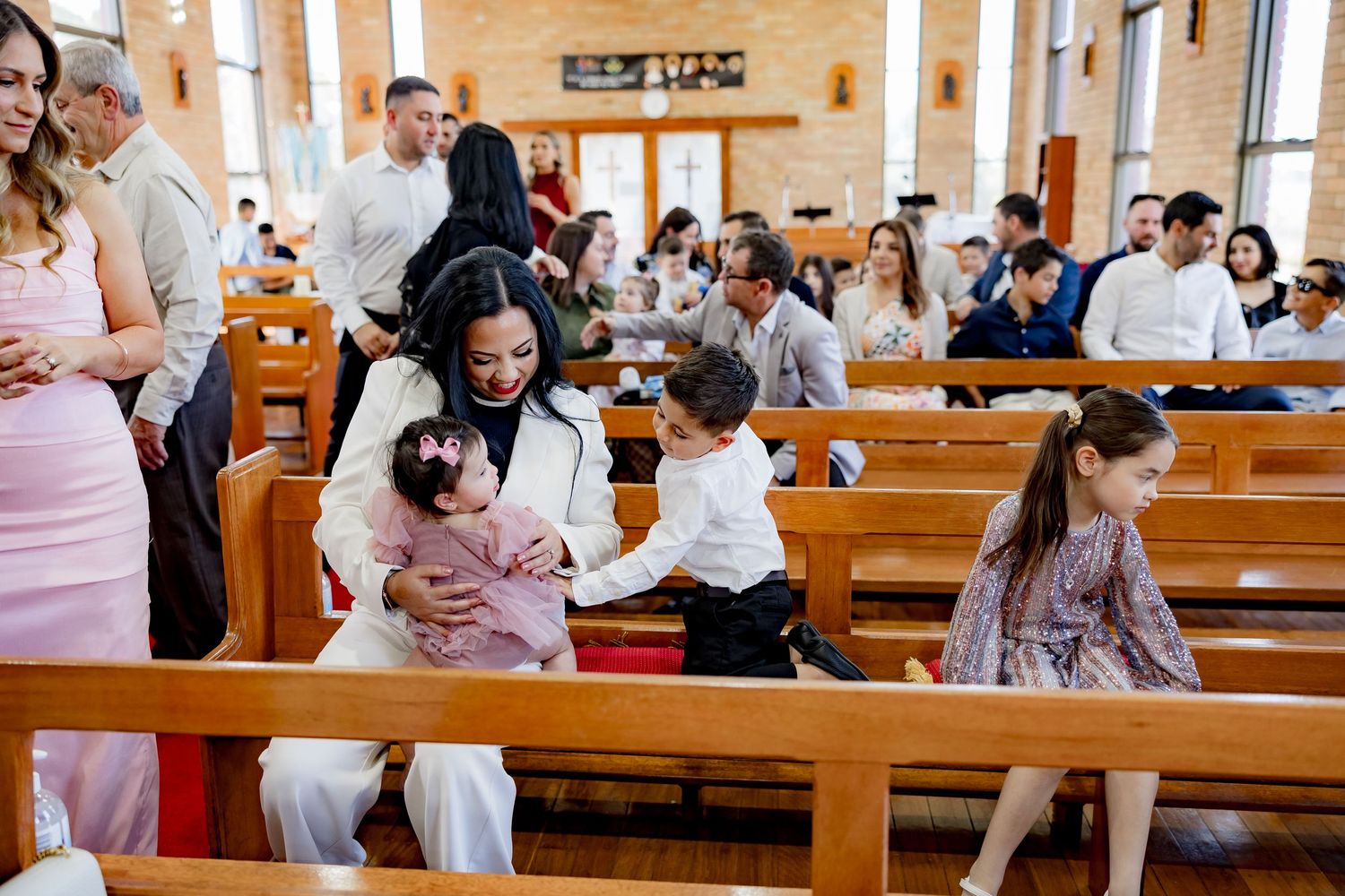 Family gathering in wooden church pews during a religious ceremony.