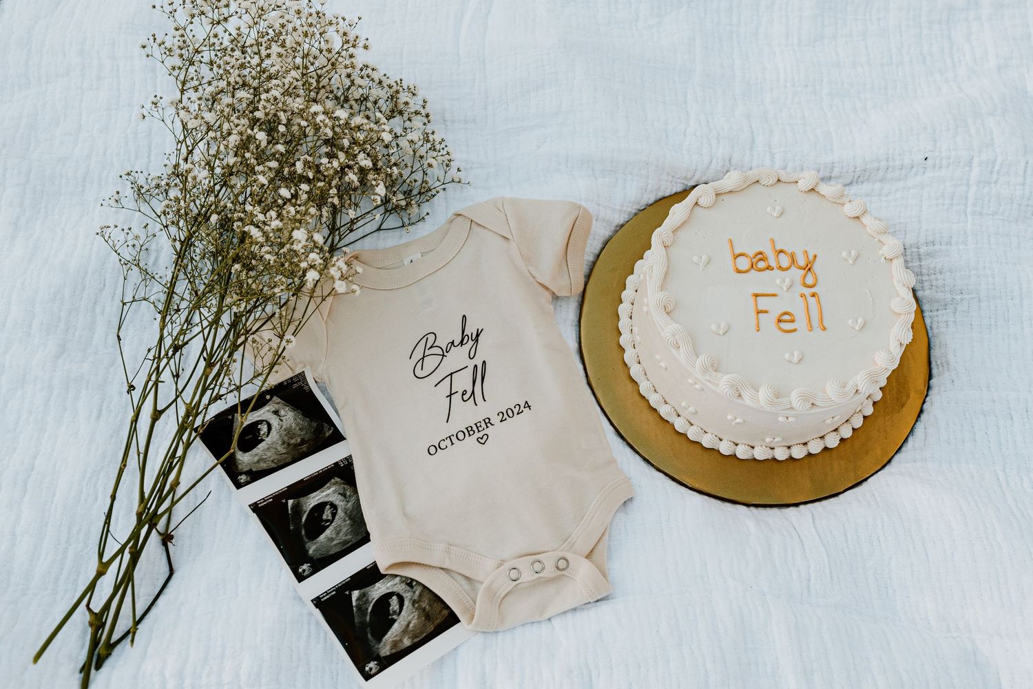 Rustic flatlay with dried baby's breath flowers, ultrasound photos, and handwritten notes on white background.