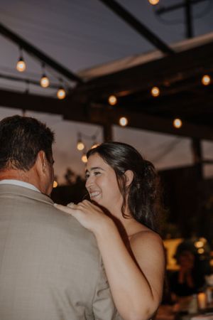 Couple dancing under string lights at an evening wedding reception.