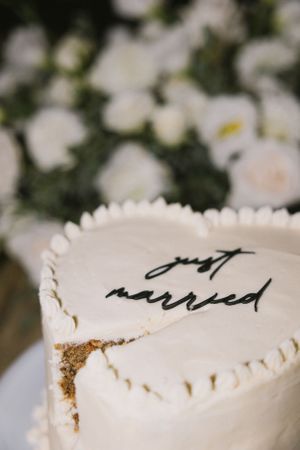 Close-up of white wedding cake with cursive text decoration.