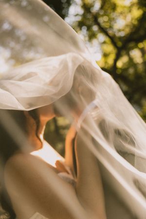 Ethereal close-up of flowing white wedding veil in natural sunlight.