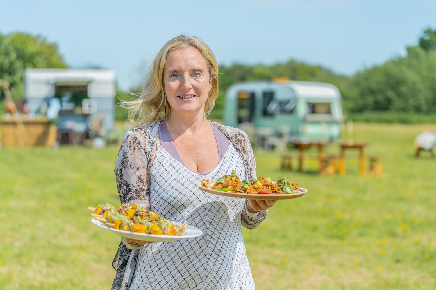 personal branding shoot in Brighton of a woman holding plates of food at a wedding fair, caravans in the background of a wedding venue